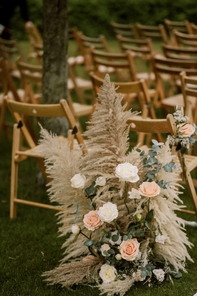 bloemstuk in pastelkleuren tegen stoelel aan van ceremonie