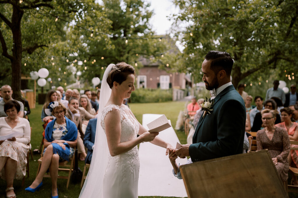 bruidspaar legt geloften af met op de achtergrond de gasten en de trouwlocatie dengh utrecht