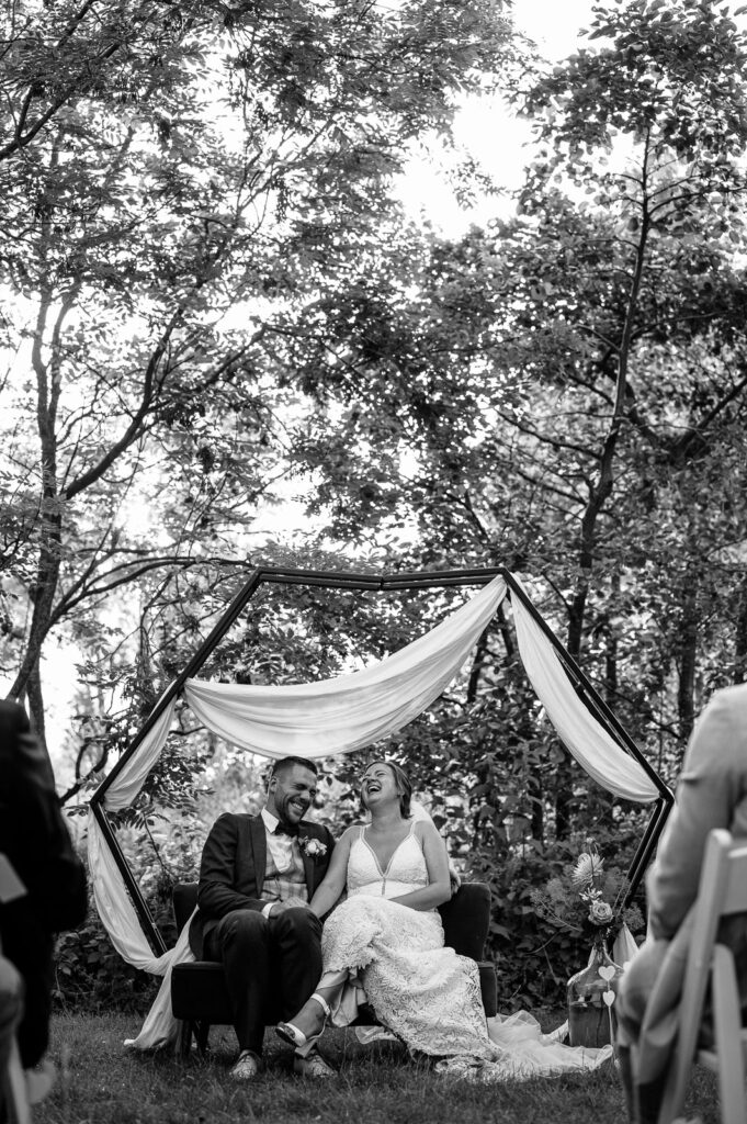 lachend bruidspaar tijdens buitenceremonie
