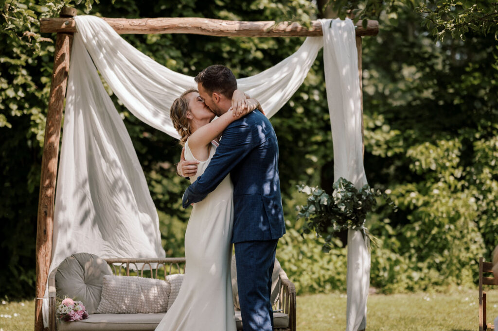 bruidspaar kust elkaar na het ja-woord tegen mooie backdrop